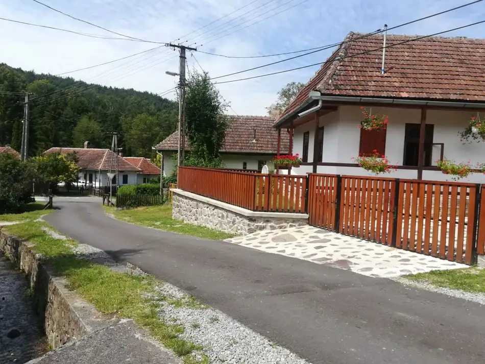 A ház az utca felől, hosszú tornáccal és muskátlis ablakokkal